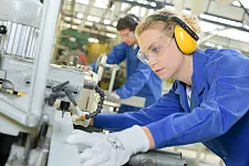 Junge Frau an industrieller Bohrmaschine