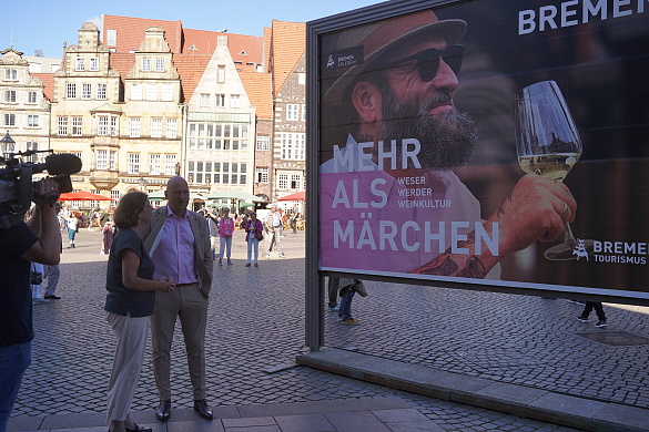 Kristina Vogt und Oliver Rau stehen vor dem Werbeplakat der bremer Tourismuskampagne